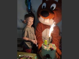 Mikołaj z dużą maskotką - orzyską Wiewiórką a przed nim tort urodzinowy z zapaloną racą.zapaloną racą