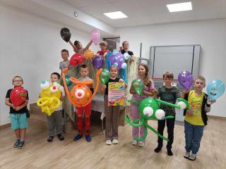 Dzieci z balonami - potworami, ozdobionymi przez siebie pozują do zdjęcia