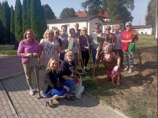 Kobiety z Klubu Seniora wraz z Panią Dyrektor Polany Kultury w Orzyszu - Joanną Kamieniecką pozują do wspólnego zdjęcia przy powstającym klombie.