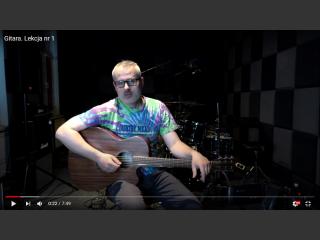 Zrzut ekranu z filmu na YouTube, na kanale Domu Kultury. Krzysztof Roszko trzyma w ręku gitarę ekustyczną. W studiu nagrań.