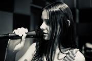 W studiu nagrań, dziewczyna trzyma mikrofon, śpiewa.