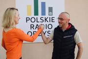 Pani Dyrektor Polany Kultury wraz z Tomaszem Staniszewskim przed Polskim Radiem Orzysz, za nimi logo radia.