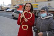 Dwie kobiety w centrum Orzysza. Kobieta z lewej trzyma drewniane serca z napisem Kocham Orzysz.