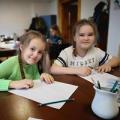 Dziewczynki przy stoliku malują na kartktach papieru.