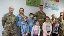 Żolnierze amerykańscy w mundurach, dzieci, nauczycielka, oraz kobieta z zespołu Orzyszanki.