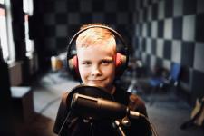 W studiu nagrań chłopiec, przed nim mikrofon.