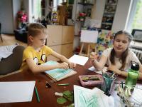 Dziewczynka i chłopiec wykonują rysunki botaniczne na zajęciach plastycznych.