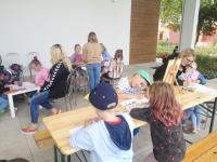 Dzieci siedzą przy stolikach i rysują