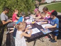 Grupa dzieci siedzi przy stole i maluje