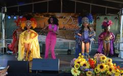Na scenie wokalistka Mili Morena w różowym kostiumie i dwie tancerki z zespołu Tropicuba w kolorowych kostiumach z pióropuszami.