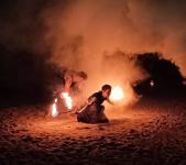 Fireshow - dwie osoby kręcące ogniem na plaży (noc).