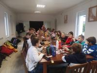 20-osobowa grupa dzieci siedząca przy stole i wykonująca kotyliony.