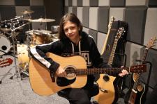 Uczestniczka zajęć z gitara w ręku podczas nauki gry. w studio nagrań.