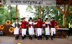 Zespół w strojach ludowych tańczy i śpiewa na scenie podczas XII Orzyskie Spotkania Folklorystyczne