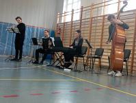 4-ososbowy zespół kameralny w trakcie występu na sali gimnastycznej w Okartowie. Od prawej: kontrabasista, pianistka, akordeonista i flecista.