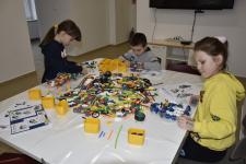 Trójka dzieci siedząca przy stole i tworząca budowle z klocków
