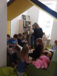 Dzieci przeglądające książki w "mobilnym domku". Na drugim planie Panie wybierające książki