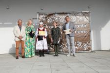 Na scenie Joanna Kamieniecka - Dyrektor Polany Kultury w Orzyszu, jury oraz kobieta w stroju ludowym. Kobieta trzyma dyplom. Za nimi baner z wydarzenia