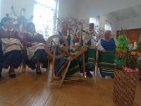 W sali lustrzanej Polany Kultury siedzą kobiety z zespołu Orzyszanki. Przed nim kołowrotek, oraz palmy wielkanocne, za nimi gwiazda