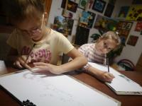 Dwie dziewczynki rysują przy stole.