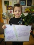Chłopiec pokazuje wykonany przez siebie rysunek.