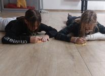 Dwie dziewczyny leżące na podłodze podczas pisania życzeń na laurkach z okazji dnia seniora.
