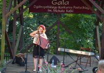 Kobieta na scenie gra na akordeonie i śpiewa. Występ na gali ogolnopolskoego konkursu poetyckiego im. Michała Kajki.